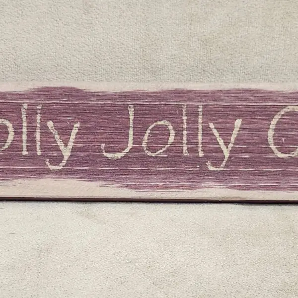 Rustic wooden sign with 'Jolly Jolly Christmas' text in white.