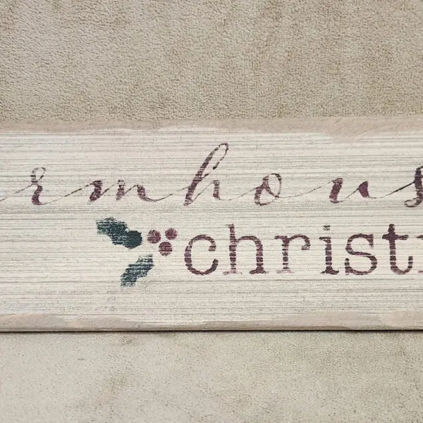 Rustic wooden sign with a Christmas greeting and holly decoration.