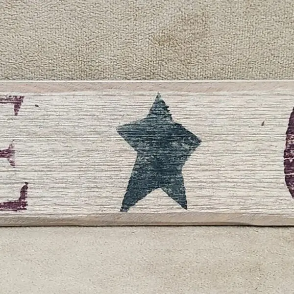A wooden plank with a painted star on a textured background.
