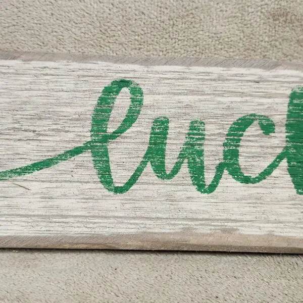 A wooden board with the word 'luck' written in green cursive.