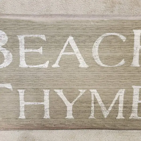 Wooden sign reading 'BEACH RHYME' in white letters.
