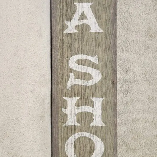 Wooden sign with white letters spelling 'ASHO'.