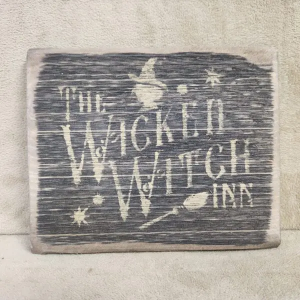 Rustic wooden sign with 'The Wicked Witch Line' and witch-themed graphics.
