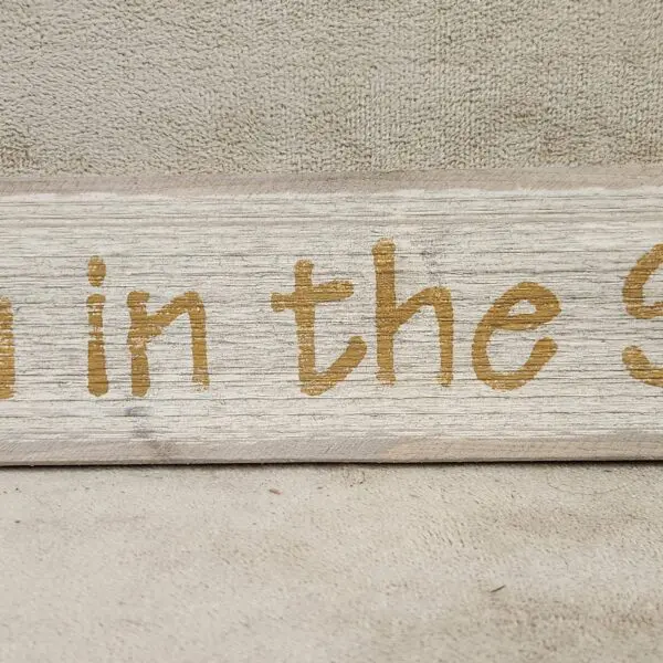 Rustic wooden sign with partial text in gold lettering.