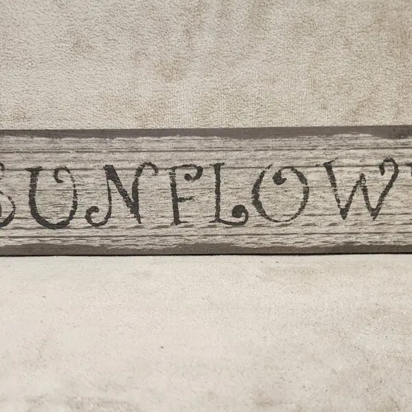 Rustic wooden sign with the word 'SUNFLOWER' in decorative letters.