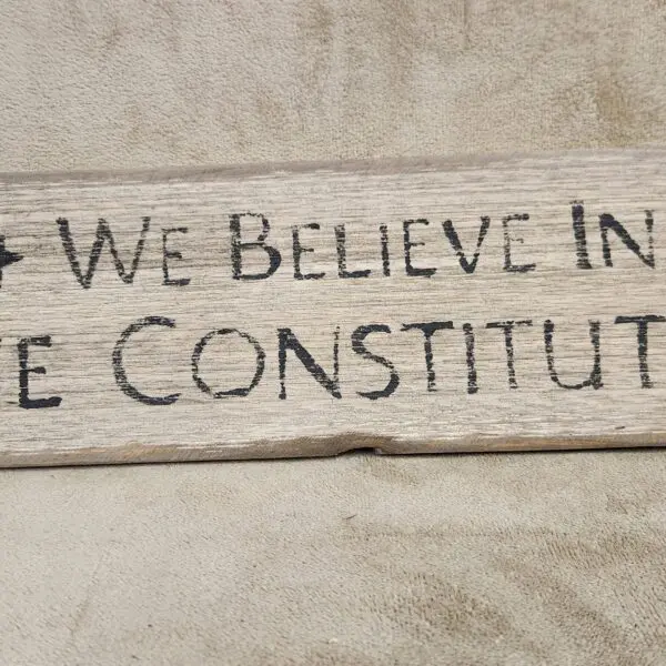 Graffiti stating belief in the Constitution on a stone wall.