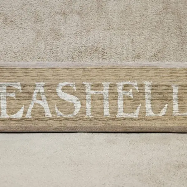 A wooden sign with the word 'SEASHELL' painted in white.