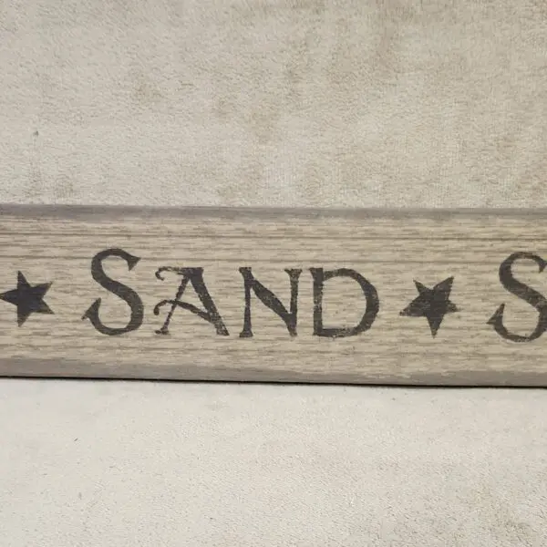 Wooden sign reading 'SAND * S'.