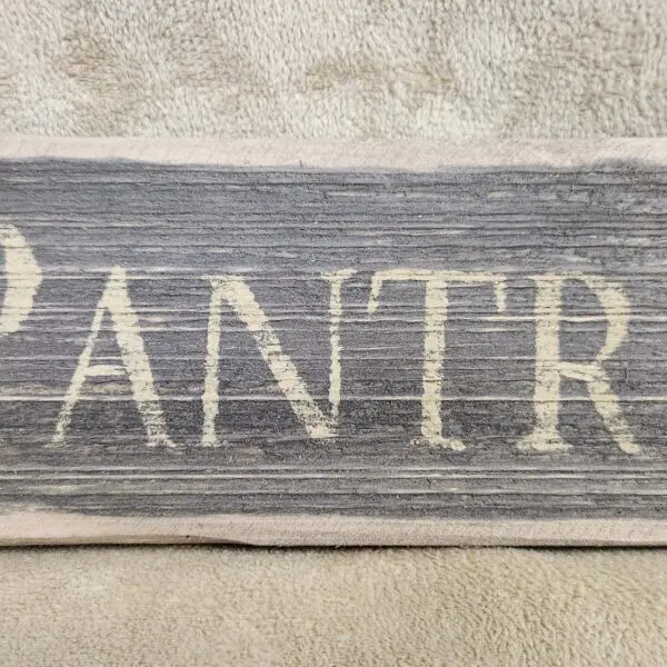 A rustic wooden sign with the word 'PANTRY' painted in white.