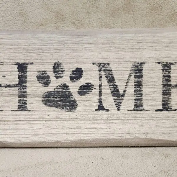 Wooden sign with the word 'HOME' and a paw print replacing the letter 'O'.