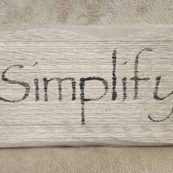 A wooden surface with the word 'Simplify' written on it.