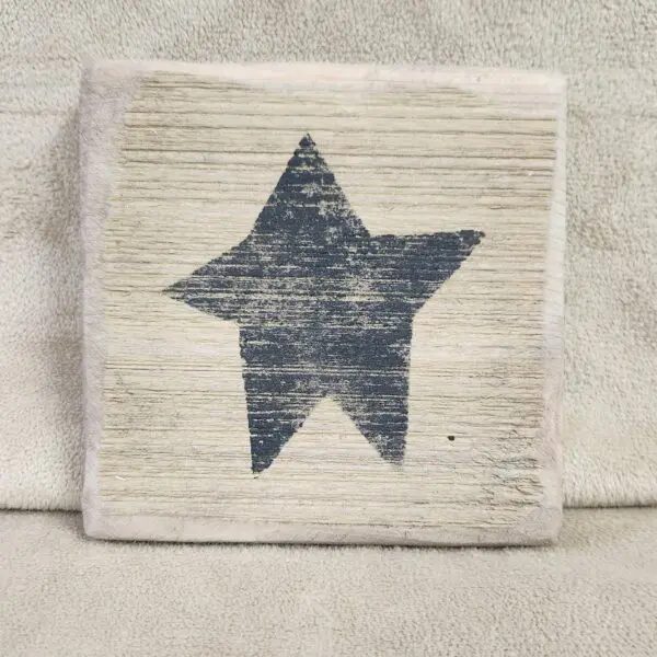 A rustic wooden block with a black star painted on it.