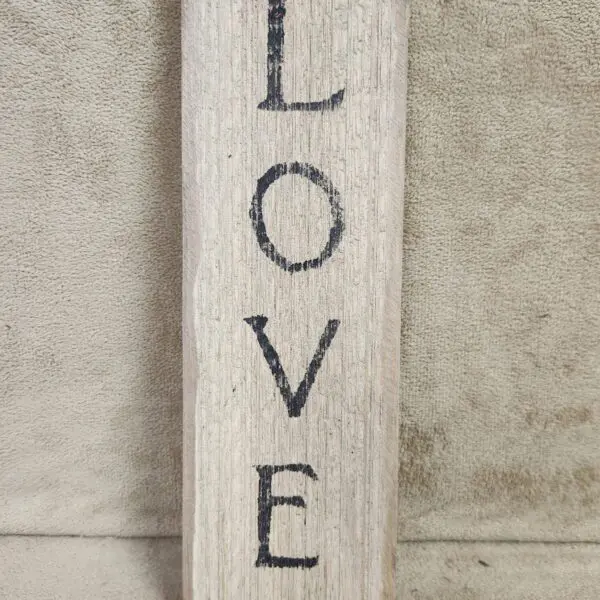 Wooden block with the word LOVE painted vertically in black.