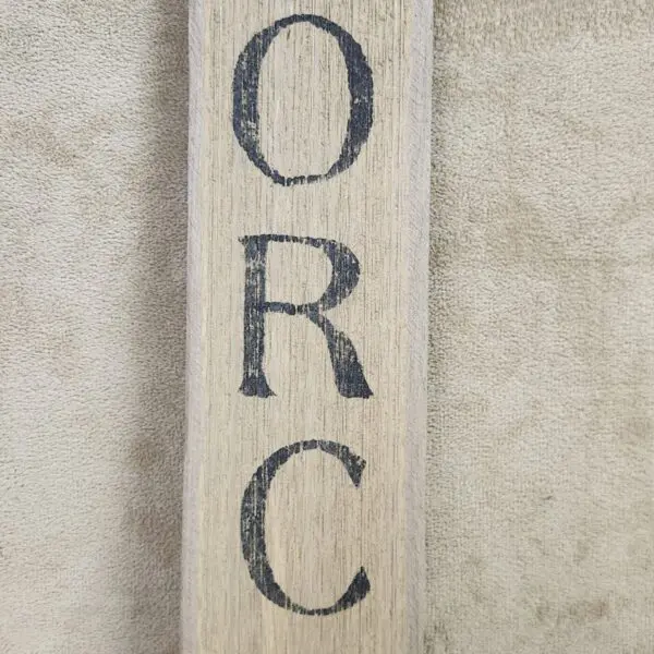 Wooden plank with the letters 'O','R','C' vertically painted in black.