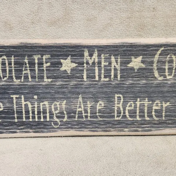 Rustic wooden sign with text about chocolate, men, and coffee.