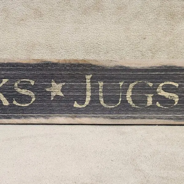 Rustic wooden sign with the words 'JUGS' and a star.