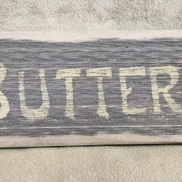 Wooden board with the word 'BUTTER' painted on it.