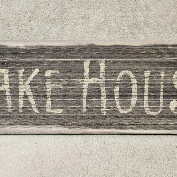 Rustic wooden sign with 'Lake House' carved in white.