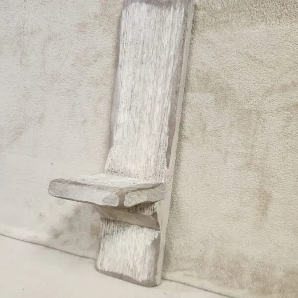 Close-up of a rustic wooden door latch on a weathered surface.