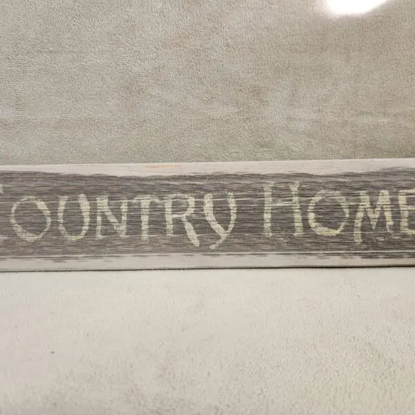 A wooden sign with the words 'COUNTRY HOME' carved into it.
