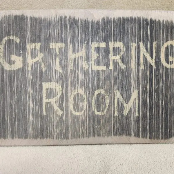 Rustic sign reading 'Gathering Room' with white letters on gray wood.
